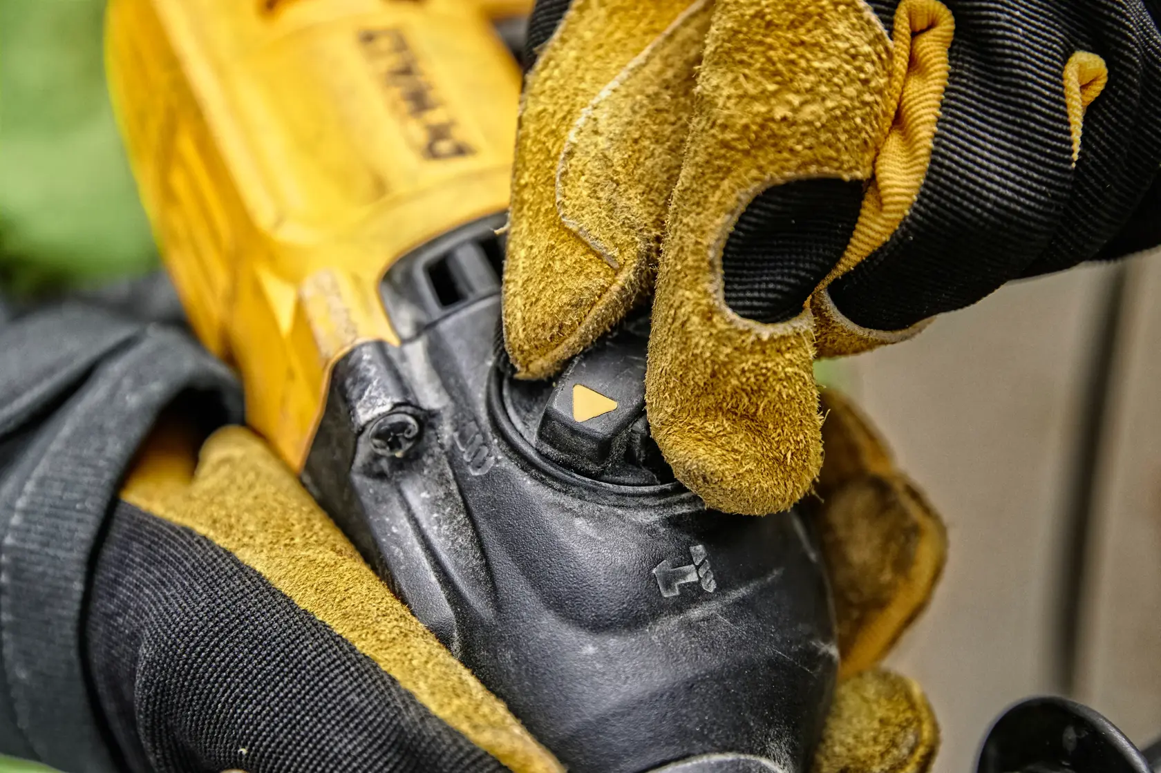 Primer plano de una persona con guantes de trabajo amarillos y negros ajustando el selector de modo en una herramienta eléctrica DEWALT.