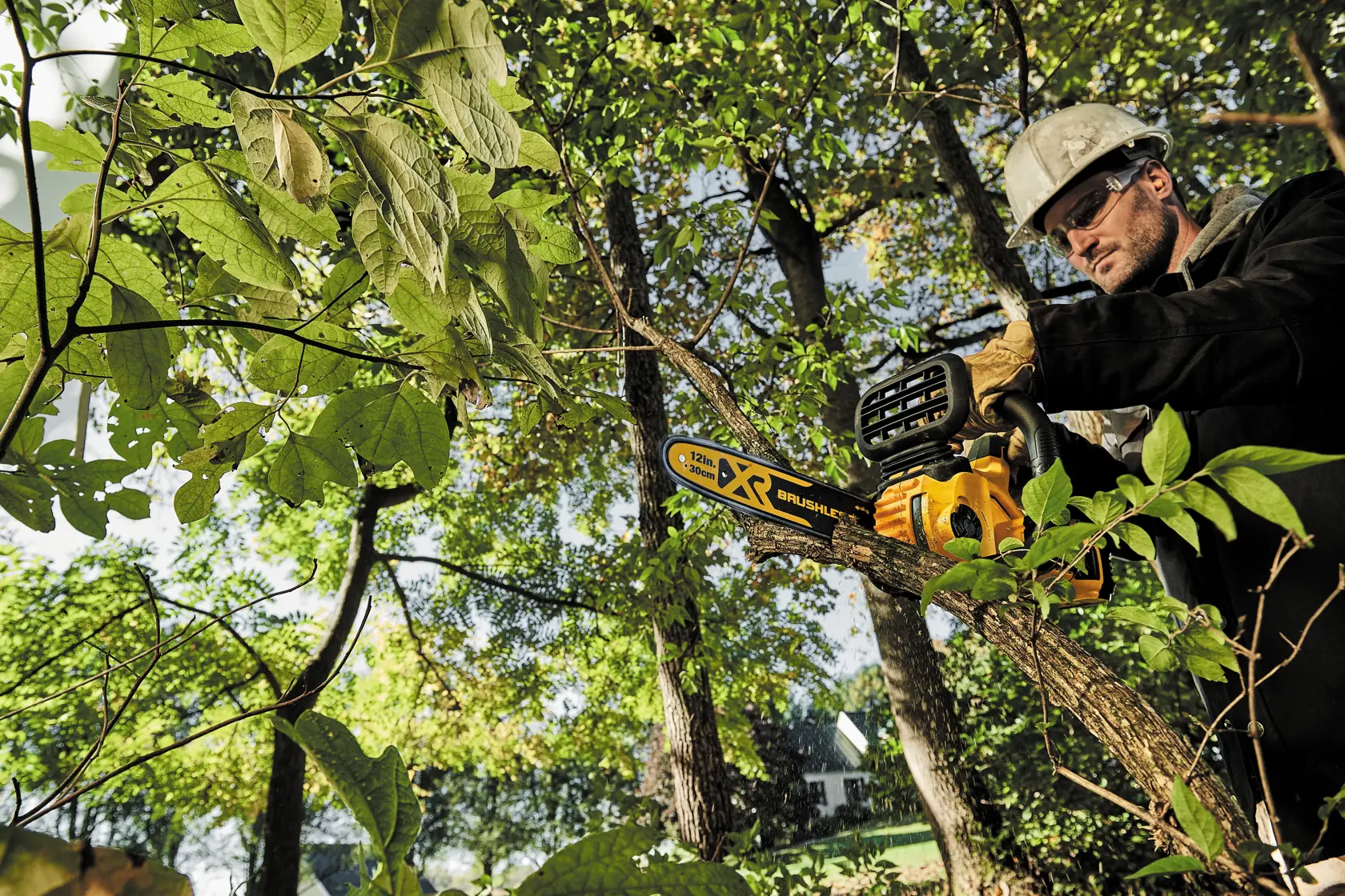 Dos personas trabajan al aire libre en un proyecto de construcción. Una usa una motosierra DEWALT para cortar una viga de madera, mientras que la otra sostiene otra herramienta DEWALT. Ambas llevan ropa casual y guantes, con sus rostros desenfocados. La construcción se realiza cerca de una casa con revestimiento.