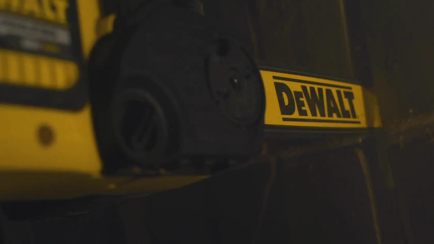 Primer plano de barra de herramienta DEWALT amarilla, parcialmente visible en luz tenue.