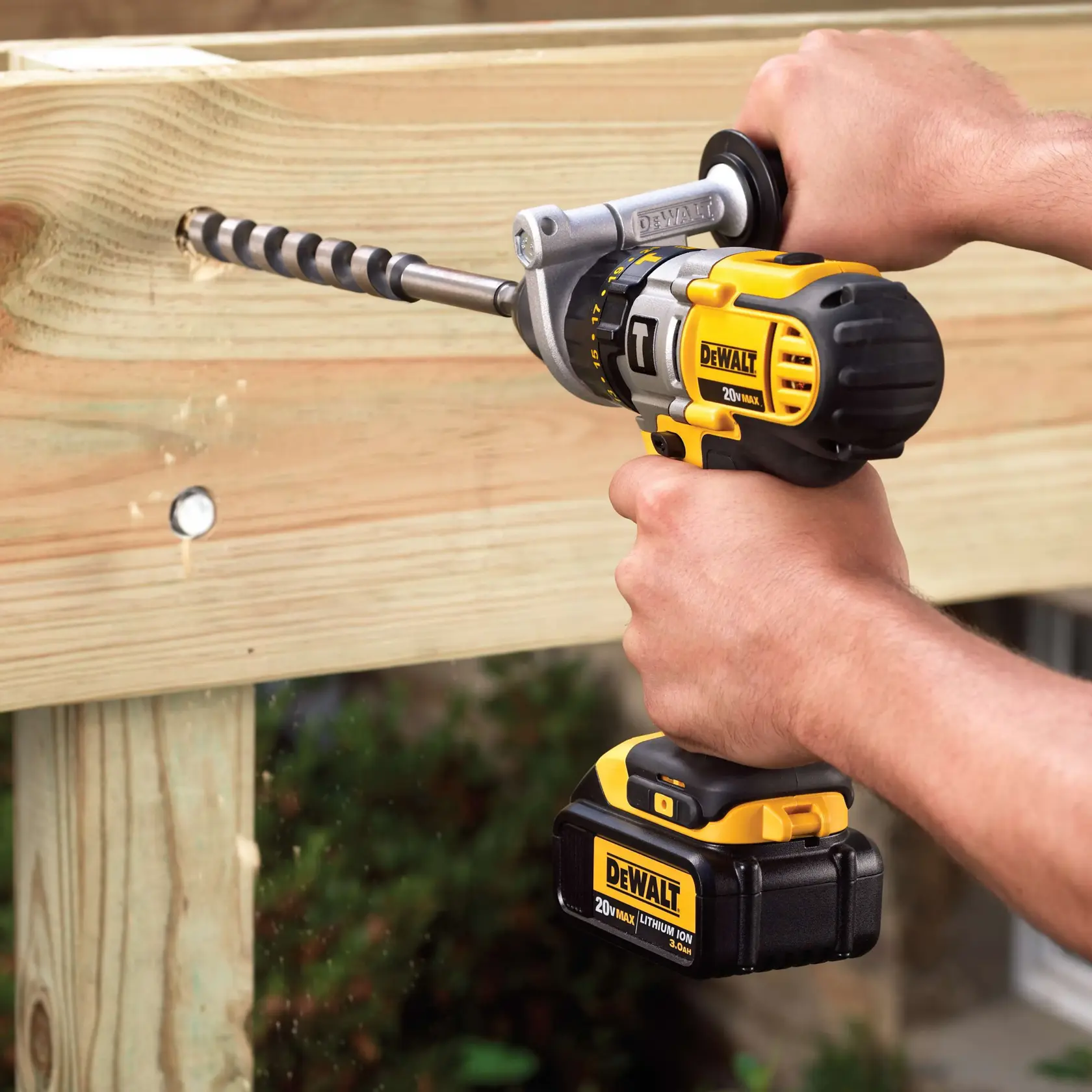 Una persona utiliza un taladro inalámbrico DEWALT para perforar un agujero en una viga de madera. El taladro tiene una broca en espiral larga y una batería de litio de 20V.