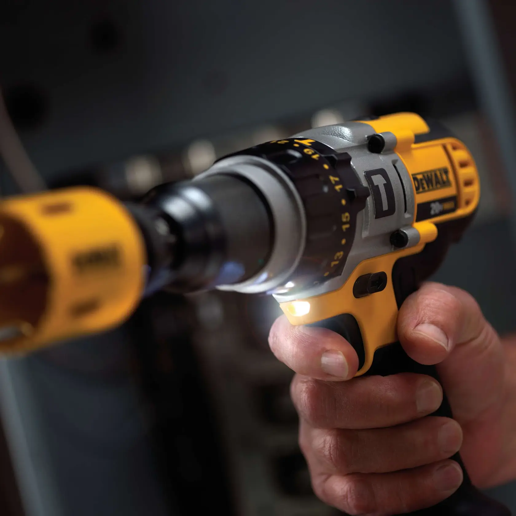 Primer plano de una persona sosteniendo y usando un taladro inalámbrico amarillo y negro DEWALT.