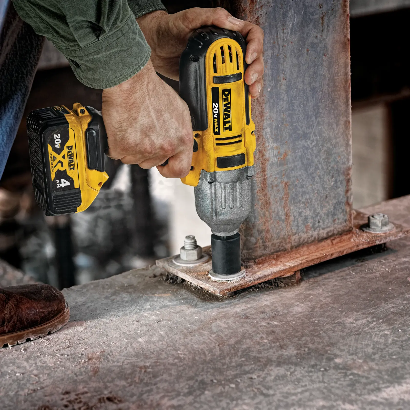 Una persona está utilizando una llave de impacto inalámbrica DEWALT 20V Max amarilla y negra para fijar un gran perno en una estructura metálica.
