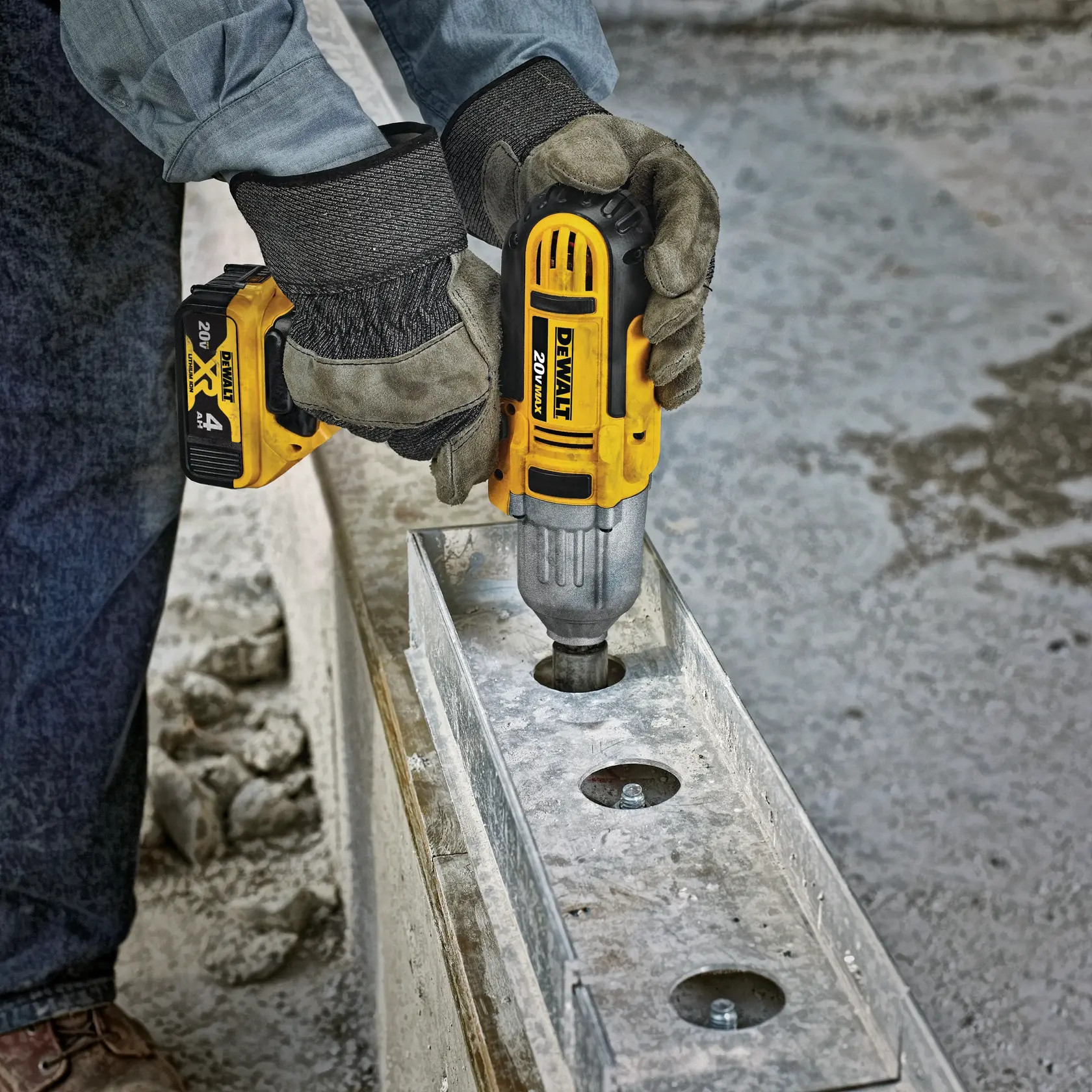 Una persona con guantes está utilizando una llave de impacto inalámbrica DEWALT de 20V para apretar un perno en una estructura metálica en una obra de construcción.