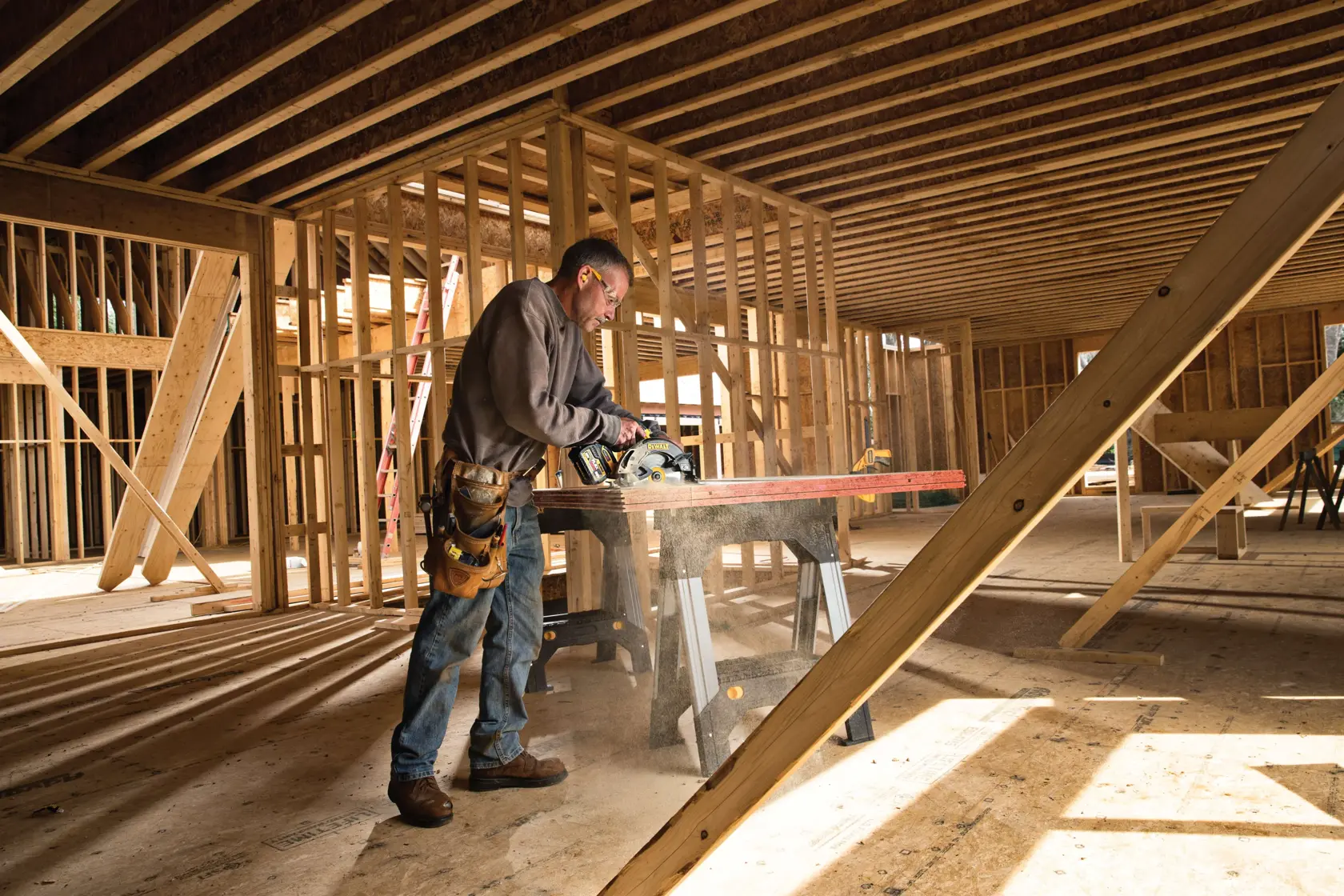 Una persona utilizando una sierra circular DEWALT para cortar madera en un sitio de construcción, rodeada de estructuras de madera sin terminar. Se observa polvo de madera en el aire mientras la herramienta está en funcionamiento.