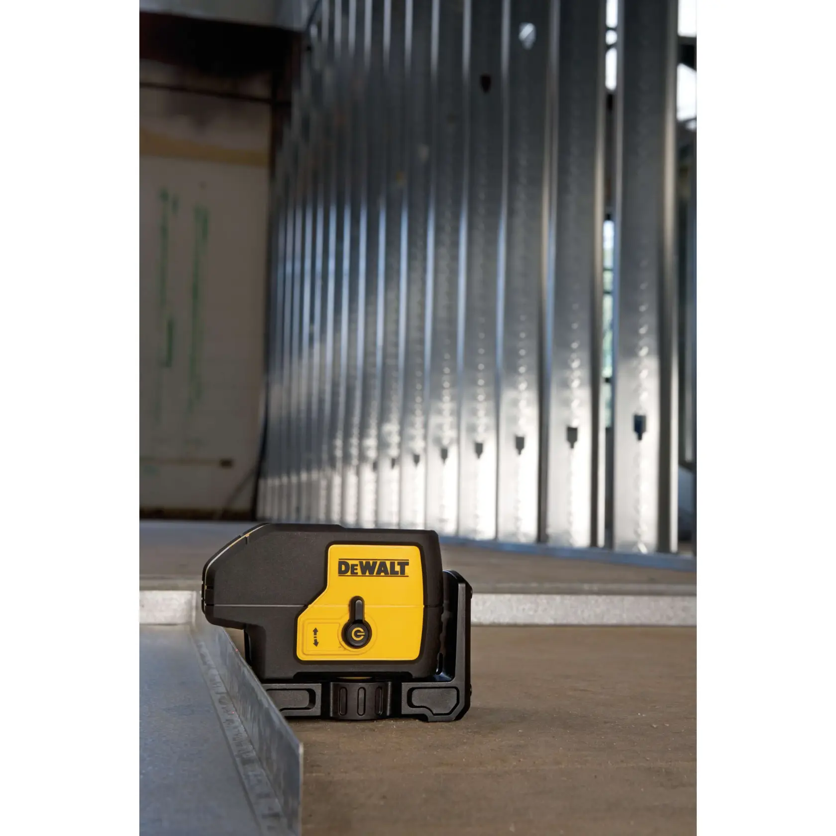 Nivel láser DEWALT DW083K en uso en un sitio de construcción con marco de pared metálico.