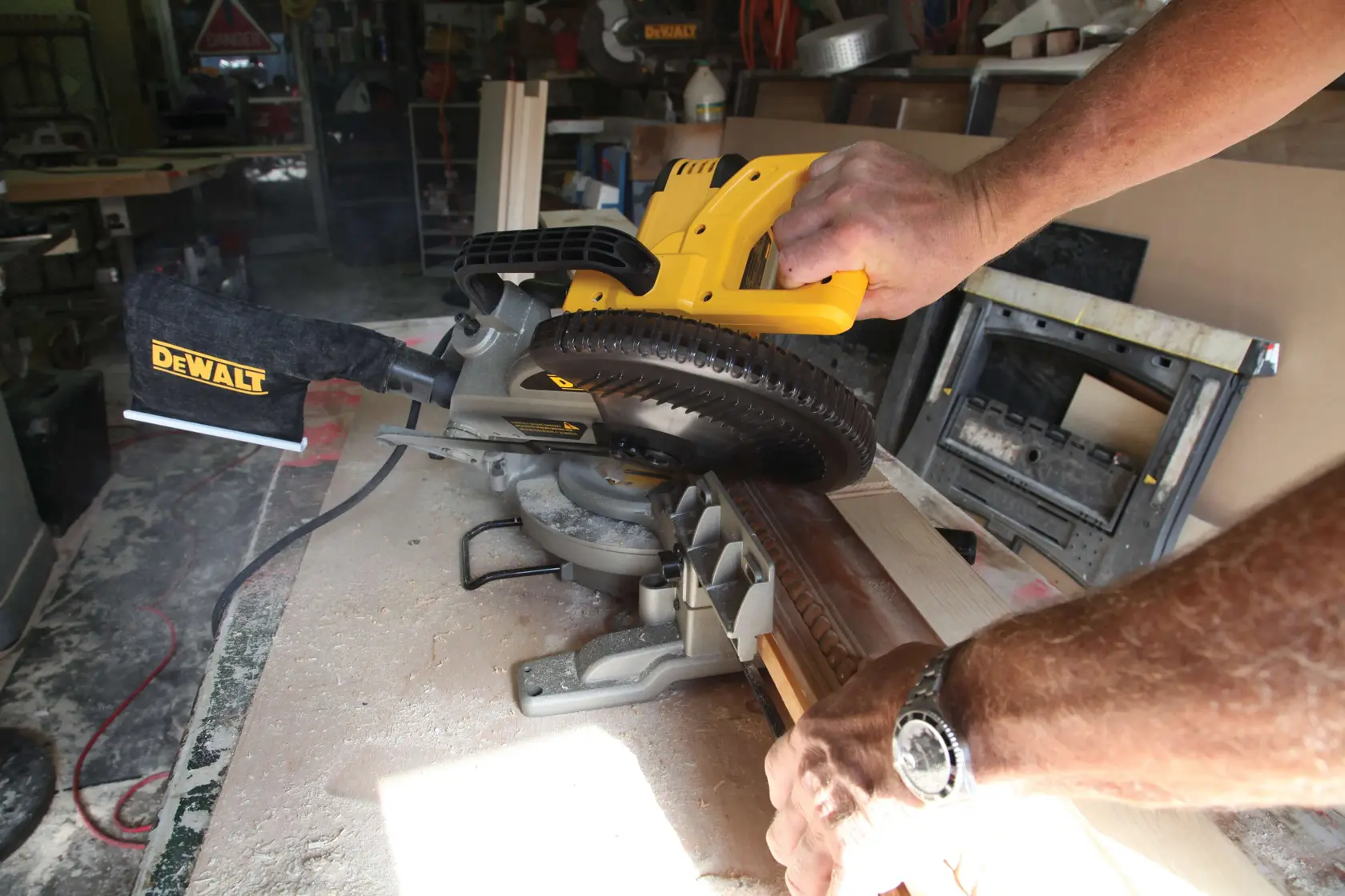 Una persona usa una sierra de inglete DEWALT para cortar una pieza de madera en un taller.